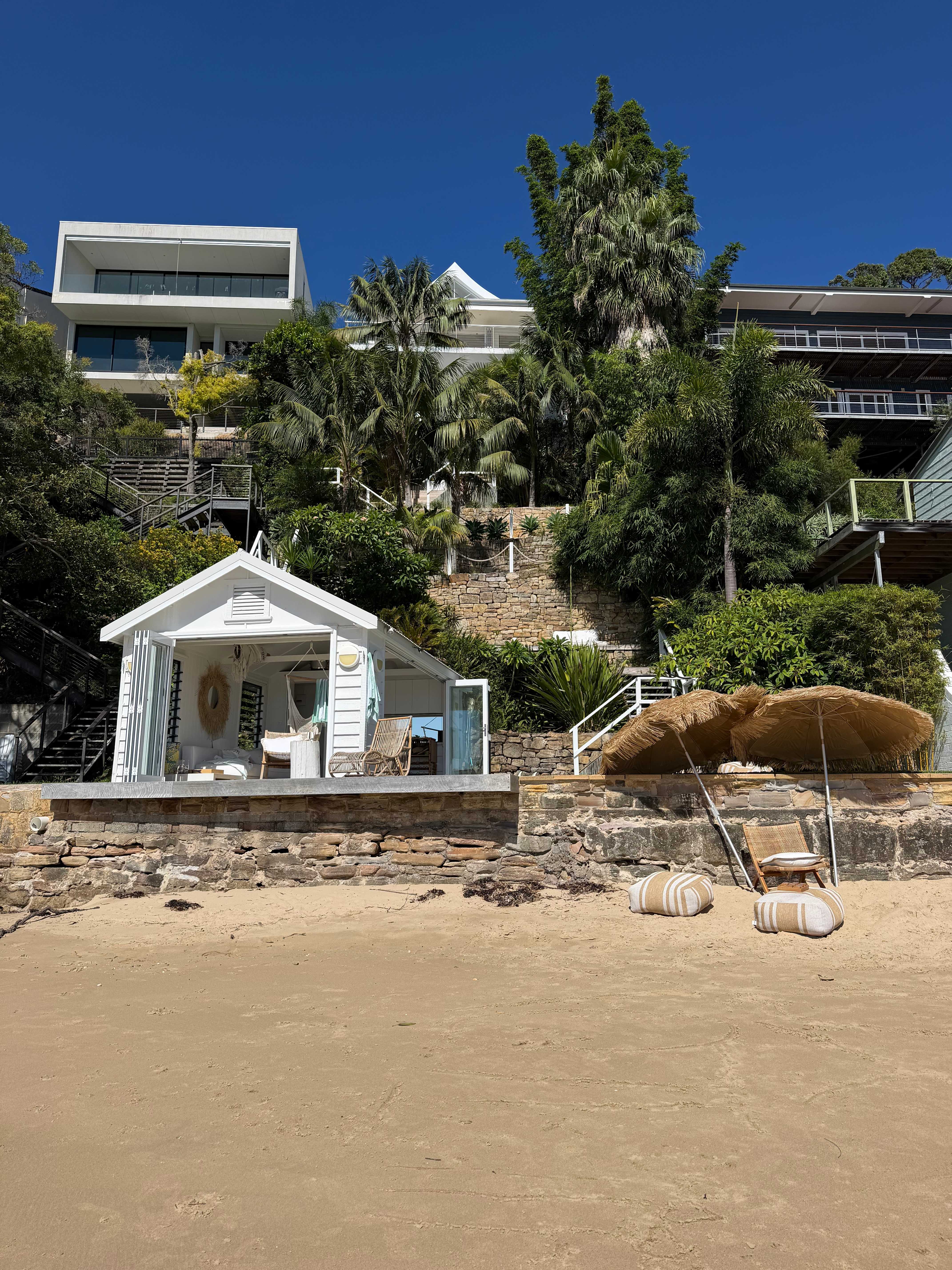 Full property view from the beach showing white beach cabin and main house
