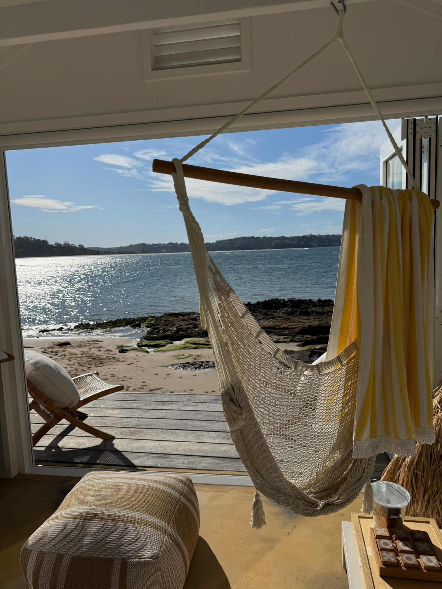 Macrame hammock chair with yellow towel and waterfront view through bifold doors