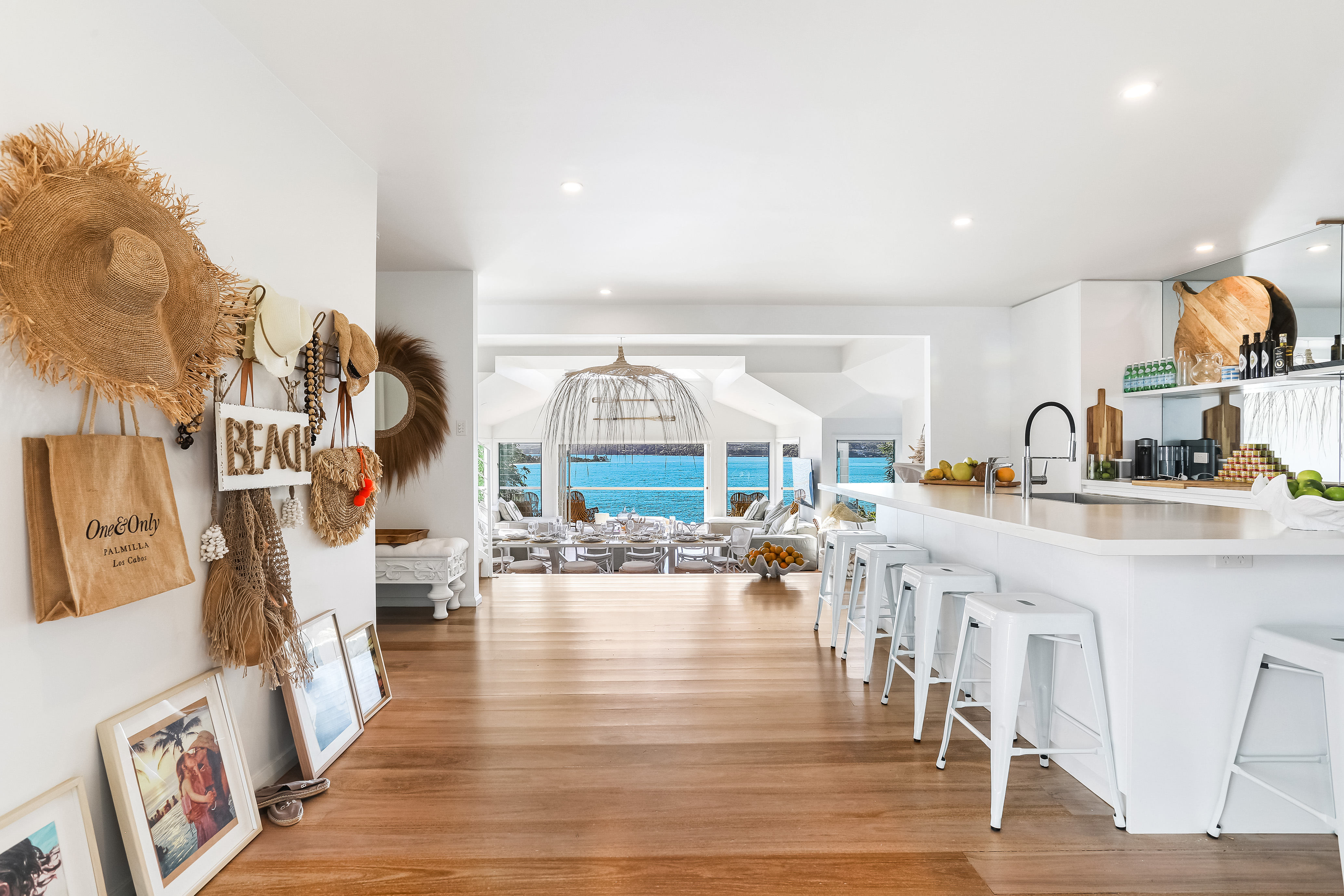 Open-plan kitchen with straw hats wall and ocean view through arched living room