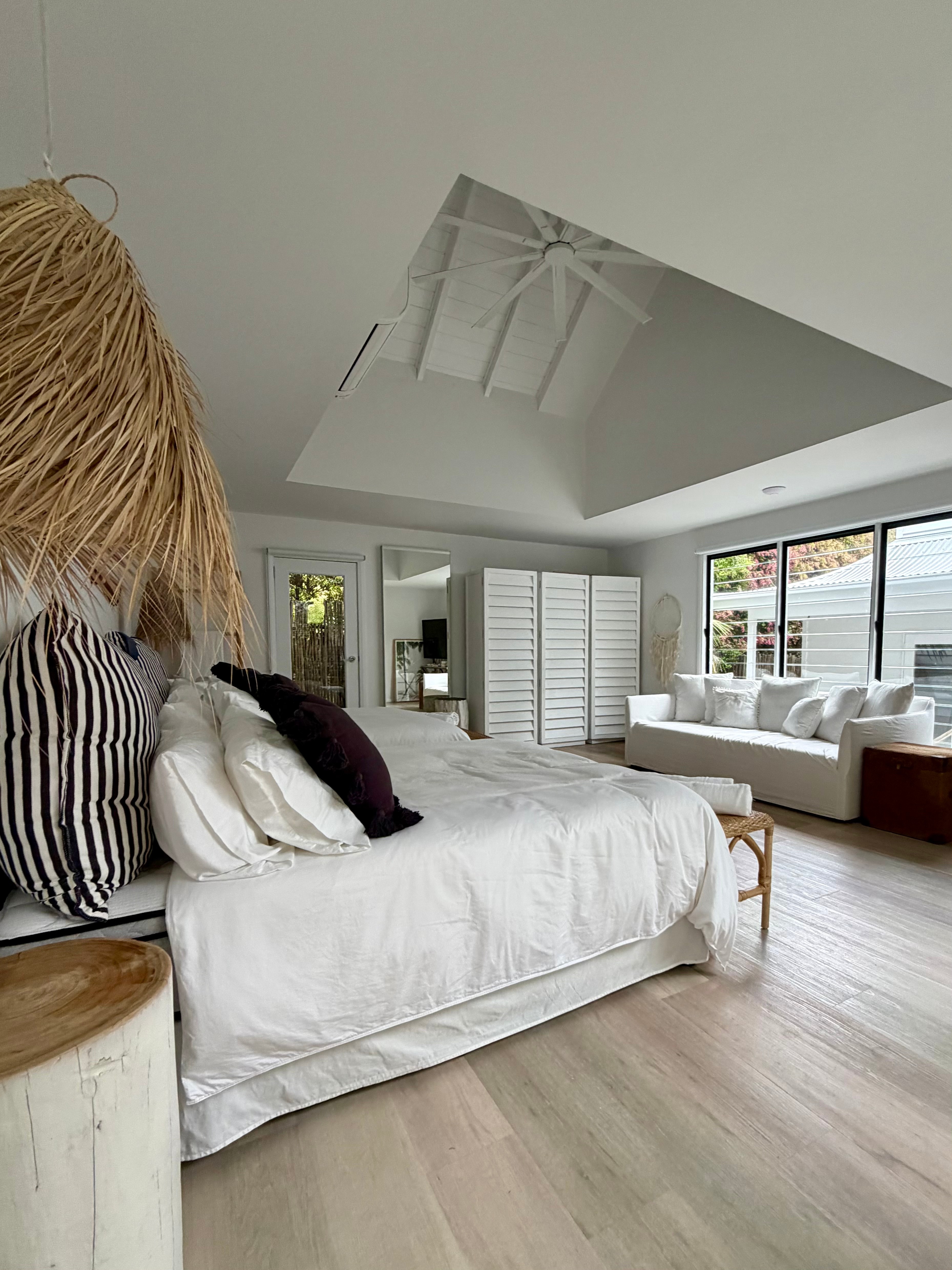 Master bedroom with vaulted skylight ceiling, rattan pendant and white linen bedding