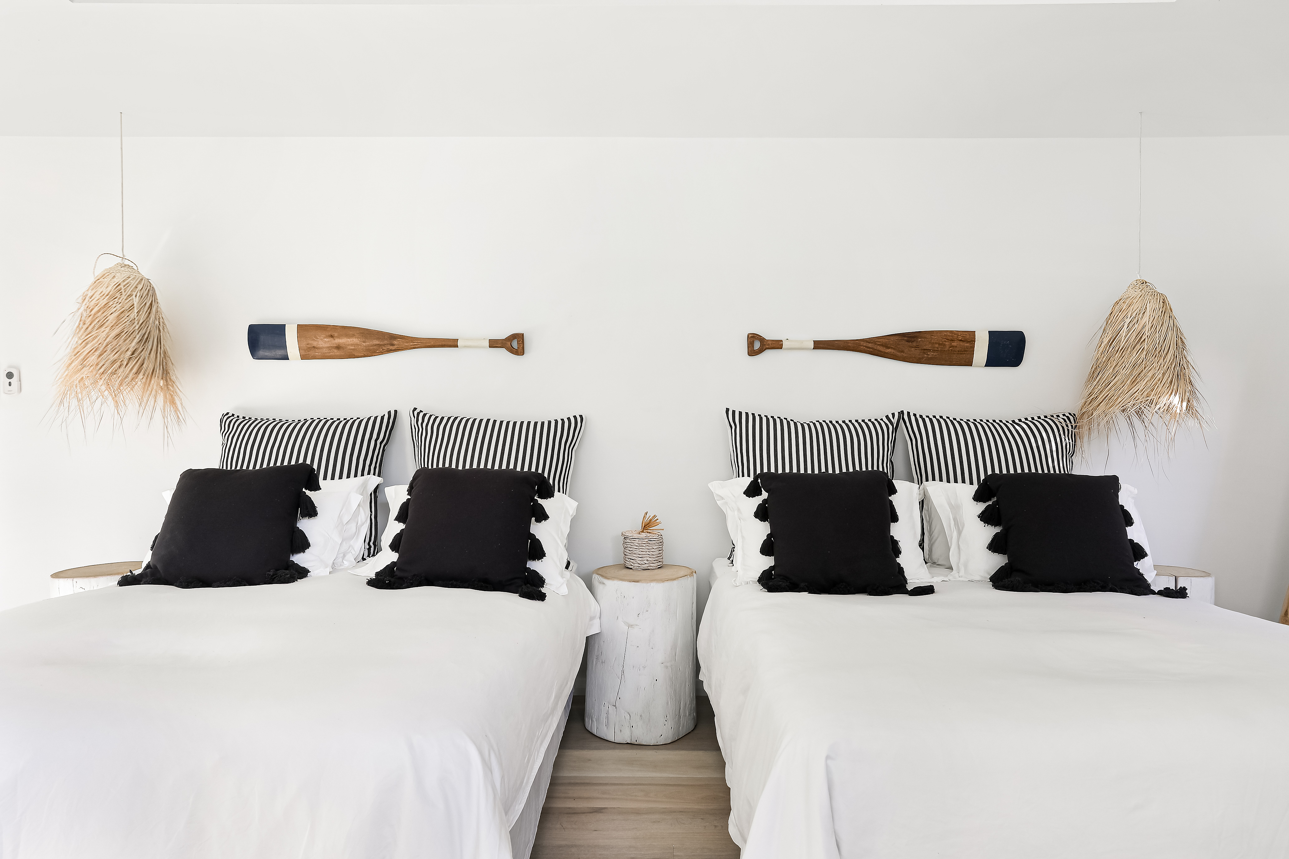 Twin beds with black and white striped pillows and painted oar wall art